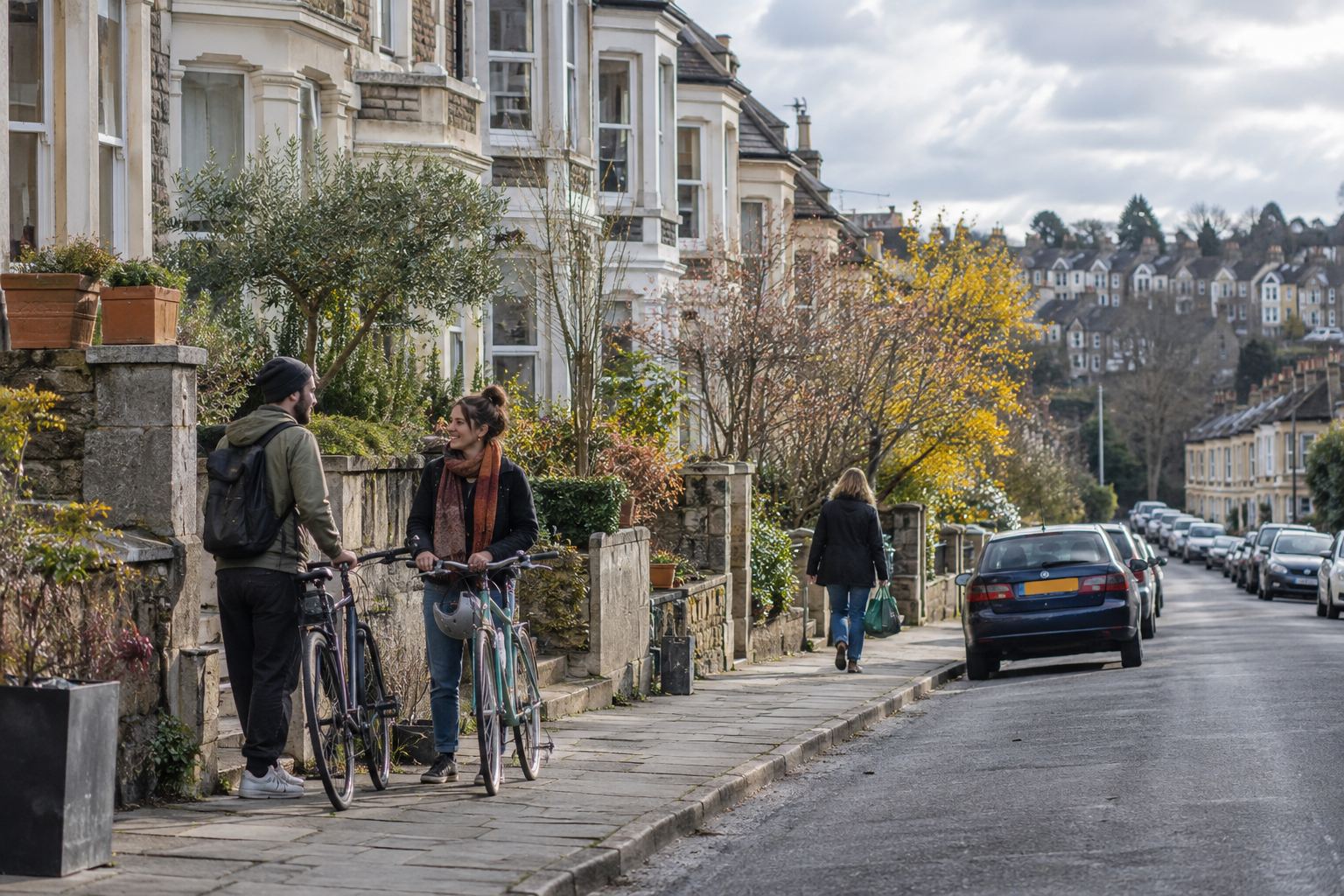 People with bicycles talking on a residential street of bay-fronted houses
